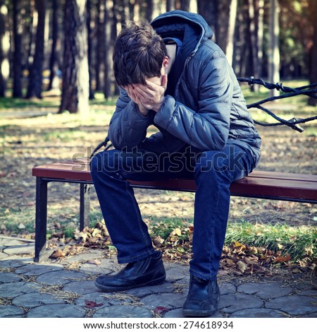 Toned Photo of Sad Young Man in the Autumn Park