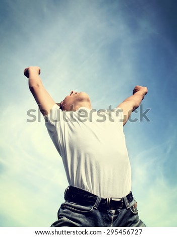 Toned Photo of Happy Young Man jump with Hands Up on the Sky Background