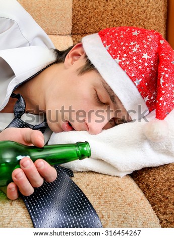 Drunken Young Man sleep in Santa Hat and Bottle of the Beer on the Sofa closeup