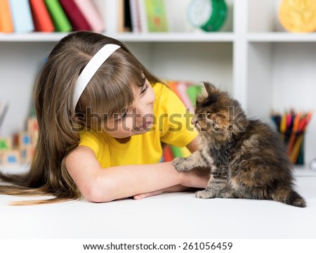 Happy little girl with her kitten at home at home