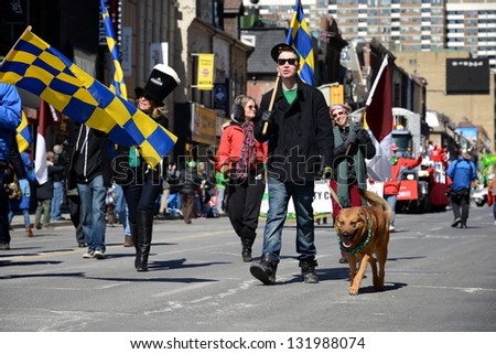 TORONTO - MARCH 17: People and dog walk on the street. Toronto\'s annual St. Patrick\'s Day parade takes place under sunny skies on Sunday afternoon March 17, 2013 in Toronto.