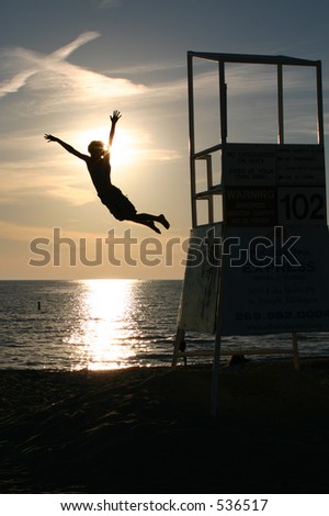 silhouette of boy jumping off lifeguard stand