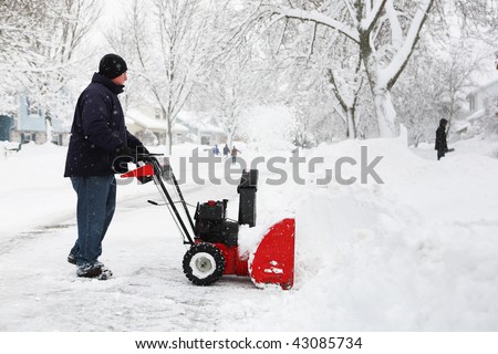 Man using a snow blower to clear out his driveway