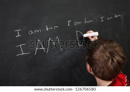Boy with poor spelling and low self esteem writing on a blackboard