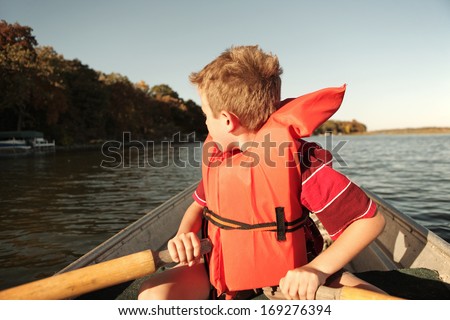 Boy rowing a boat on a lake - stock photo