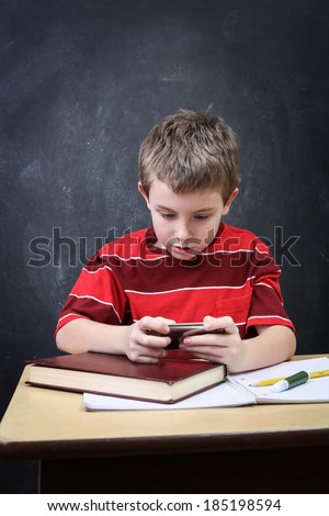 School boy playing a video game while at his desk
