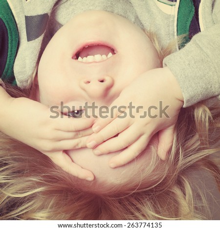 Upside down toddler boy playing peek a boo. Instagram effect.