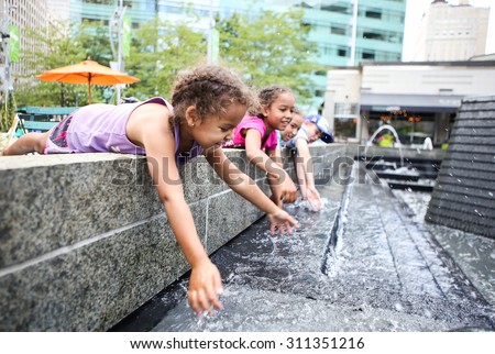 Children playing in a city fountain. Shallow focus on girl\'s face.