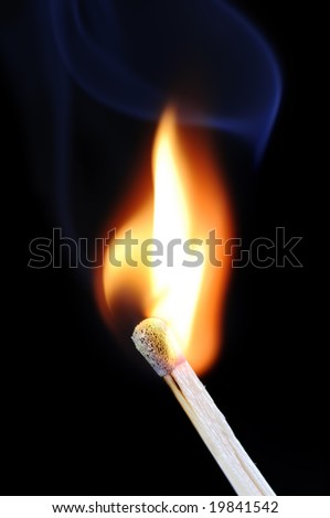 Burning fire of a match on black background with blue smoke above.