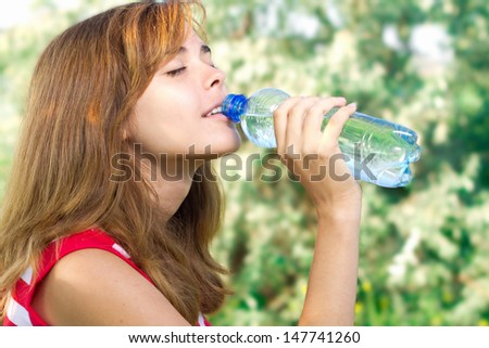 beautiful girl drinks water from a bottle on the nature