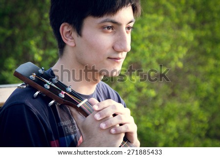 young guy playing guitar in the park