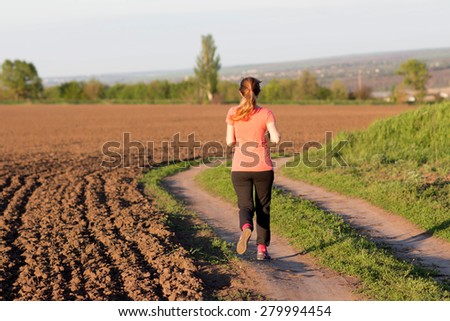 Girl in a sports suit runs along the field