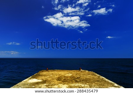 Beautiful summer landscape - concrete pier on the background of the dark blue sea on a sunny day, Crimea