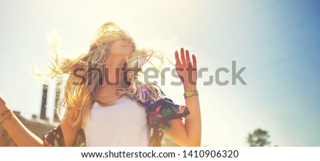 Attractive happy young woman in white t shirt flying hair enjoying her free time at sunset outdoor. Beauty blonde girl portrait at summer. Freedom lifestyle springtime concept. Sun glow on background