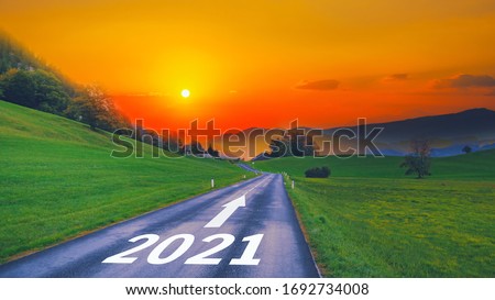 Empty open asphalt road and New year 2022 concept. Driving on empty road goals against sun in mountains to upcoming 2021 and leaving behind old years. Concept for growth success, passing time future.