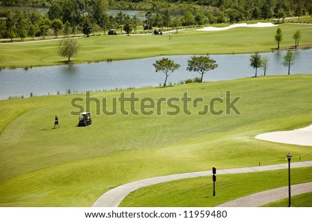 A well-tended golf green with sand traps, golf carts and players in Florida.