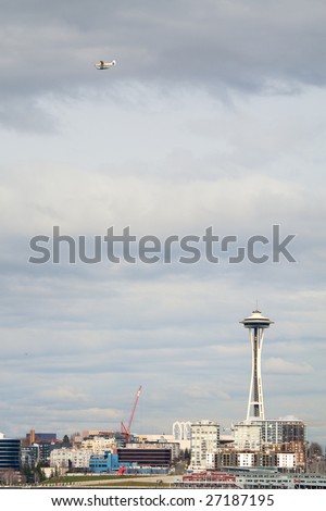 A float plane flies over the Seattle waterfront with the Space Needle shown.