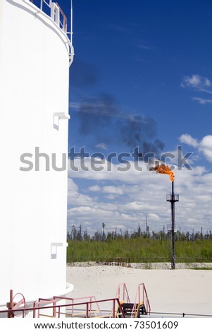Oil and gas industry. Work of oil pump jack on a oil field.. Burning of gas on a petrochemical plant