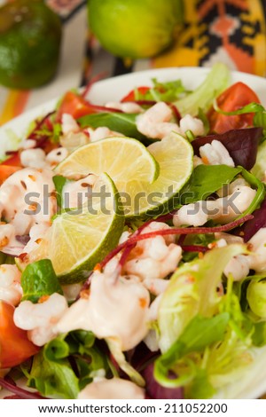 Oriental salad with different kinds of lettuce, cocktail prawns, cherry tomatoes and mayonnaise sauce. Typical mexican fresh salad, decoration with fresh pieces of lime.