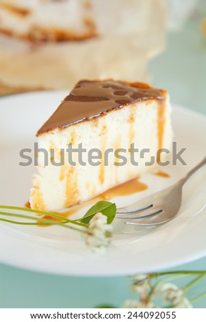 Piece of toffee cheesecake with crashed biscuits and caramel  on the top. Cheesecake was prepared with flour, white cheese, sugar, eggs and butter. Presented on white plate with silver knife.