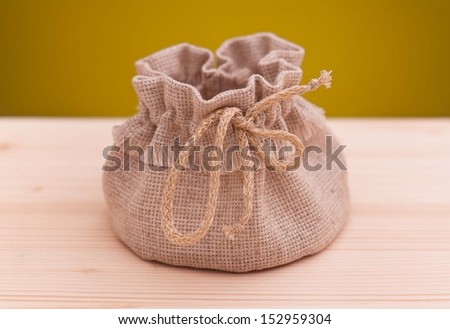 Empty sack on a wooden surface over dark yellow background
