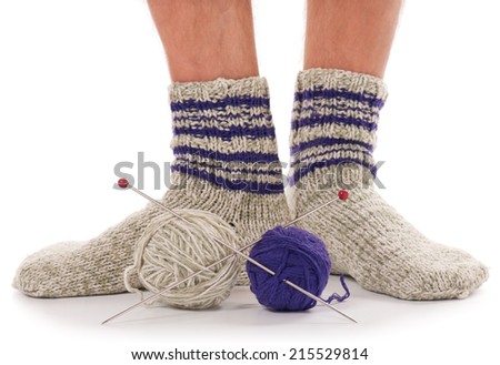Legs of caucasian man in knitted warm socks over white background. Focus on the thread balls