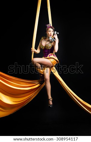 Aerial gymnast sitting on canvases in a sexual pose and talking on the phone