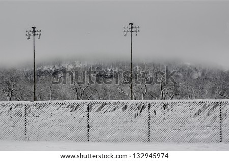 Snowy fences with mont-royal mountain in the background, covered with fog, montreal