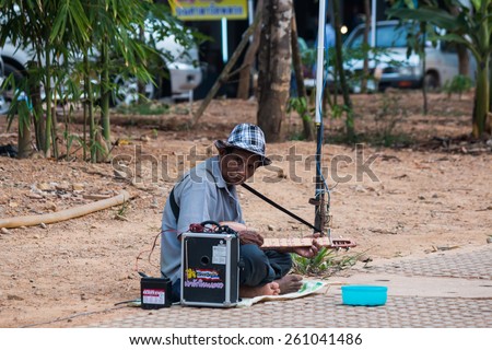 CHANTHABURI, THAILAND - MAR 13 : One poor man plays local musical instrument for money on March 13, 2015 at sidewalk in Chanthaburi Province, Thailand