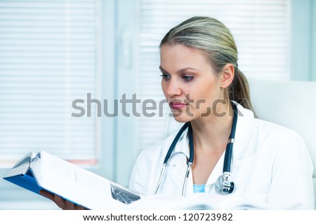 Pretty Young Female Doctor Is Studying from a Medical Book in Her Ambulance