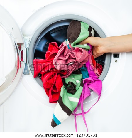 Housework: Detail of Female Doing Laundry, while Putting Colorful Clothes into the Laundry Machine