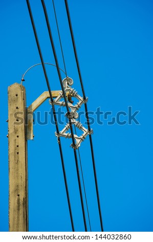 electrical post with electrical wire locker and power lines  against bright blue sky.