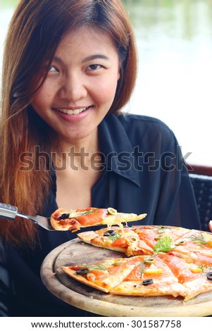 Women looking happy with a pizza in front of her.