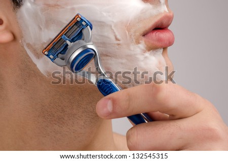 Shaving the beard with a razor. Close up on a young man shaving his beard in the morning with a razor.