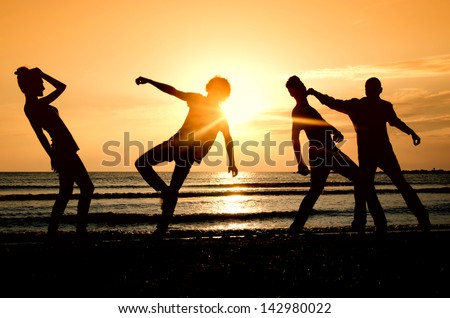 Group of happy people parting on the beach at sunrise, people fighting and getting fit in the morning