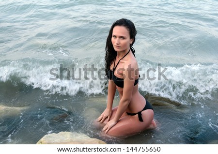 Perfect woman in swimsuit enjoying her time on the beach, waves hit her fit body