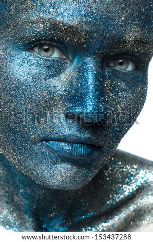 Beautiful face of a woman covered in glitter. Close up of a woman\'s face covered in blue glitter.