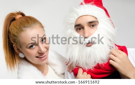 Beautiful red hair woman dressing her boyfriend as Santa Clause