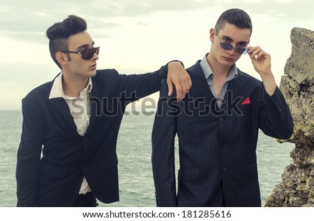 Two young businessman posing fashion at the beach and enjoying their vacation