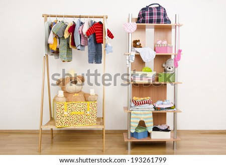 Dressing closet with complementary clothes arranged on hangers.Wardrobe of newborn,kids, babies full of all shades of blue an orange clothes, shoes,accessories and toys