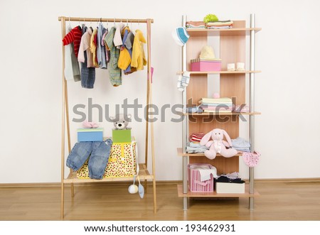 Dressing closet with complementary clothes arranged on hangers.Colorful wardrobe of newborn,kids, babies full of all clothes, shoes,accessories and toys