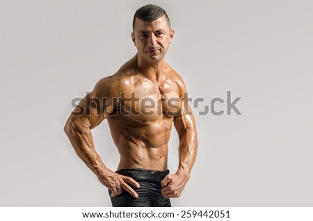 Close up on perfect abs. Strong bodybuilder with six pack.Strong bodybuilder man with perfect abs, shoulders,biceps, triceps and chest, personal fitness trainer flexing his muscles
