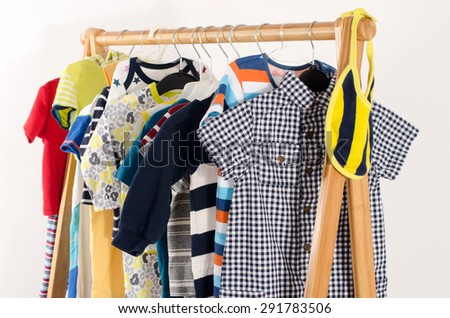 Dressing closet with clothes arranged on hangers.Colorful wardrobe of newborn,kids, toddlers, babies full of all clothes.Many t-shirts,pants, shirts,blouses,yellow hat, onesie hanging