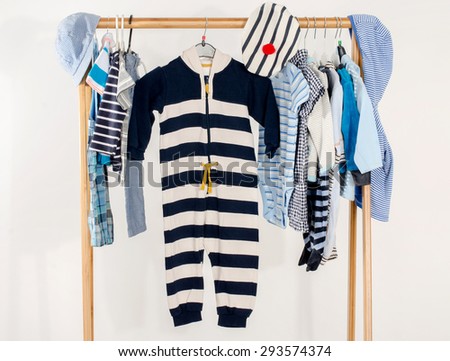 Dressing closet with clothes arranged on hangers.Marine wardrobe of newborn,kids, toddlers, babies on a rack.Many t-shirts,pants, shirts,blouses, onesie hanging