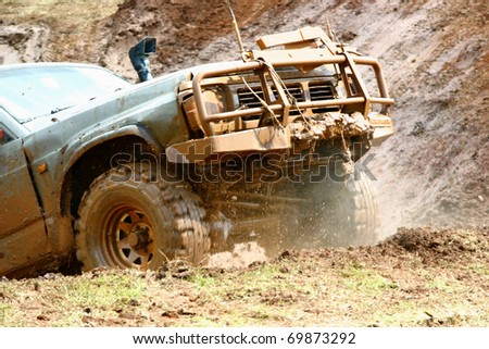Off road vehicle coming out of a mud hole hazard. Mud and smoke around