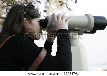 Girl watching the city through the observation binoculars