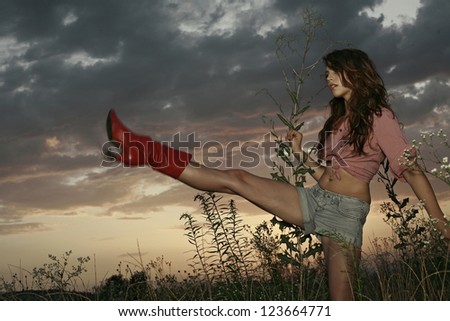girl in the field with a raised leg, sunset