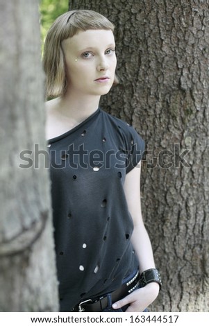 image of beautiful girl hiding and looking behind the tree