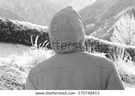 a rare look at the person in checkered winter jacket in the background mountains, black and white