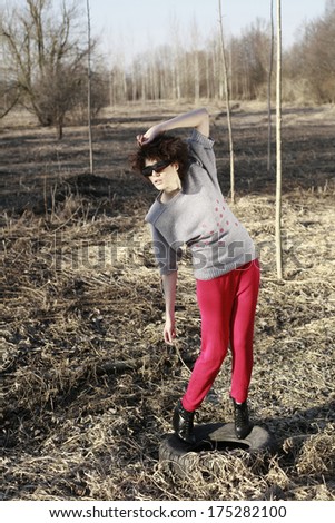 image of funny curled girl in autumn nature posing with sunglasses and wears red shorts